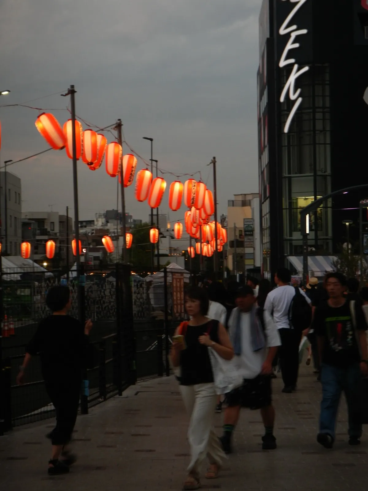 Red paper lanterns above a busy street in Japan at dusk