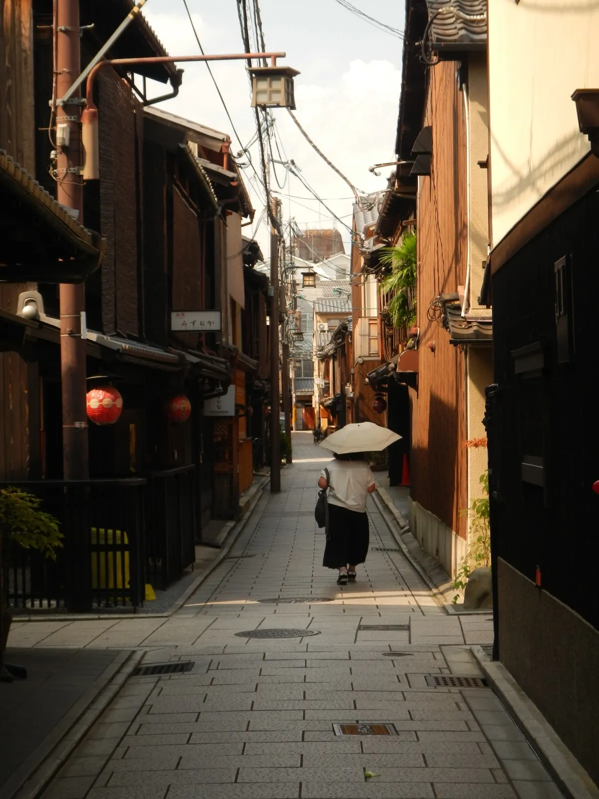 Narrow lane in Kyoto with a single person walking under an umbrella