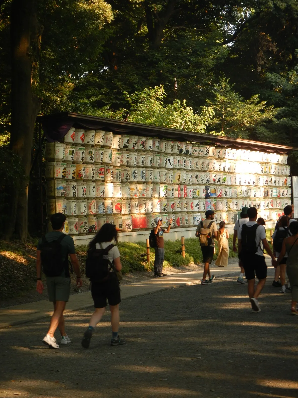 Wall of decorated sake barrels in Kyoto with people walking past