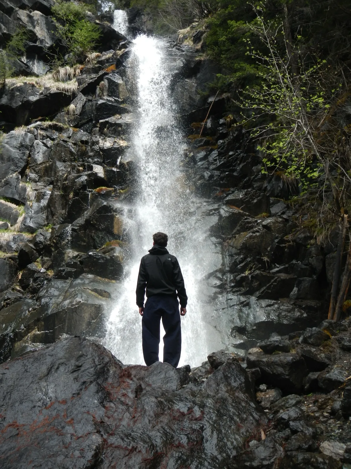 Person standing in front of a waterfall in the Swiss mountains